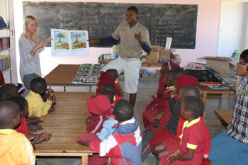 Barn i ett klassrum lyssnar på ett par lärare. Foto.